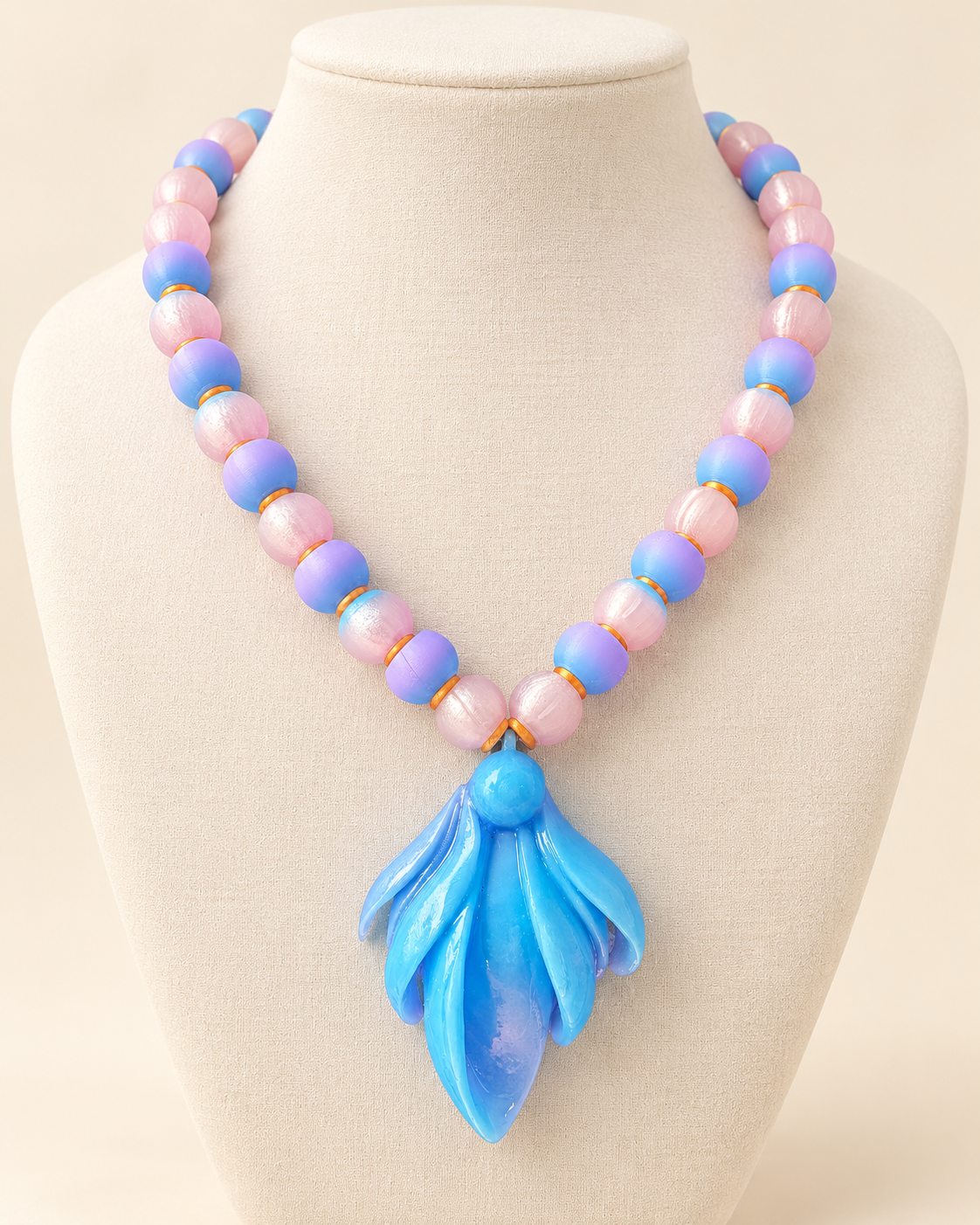 Laguna Frailejón necklace by CATE, pink and lavender ombré beads with a bright blue UV resin finish pendant, shown on a bust.