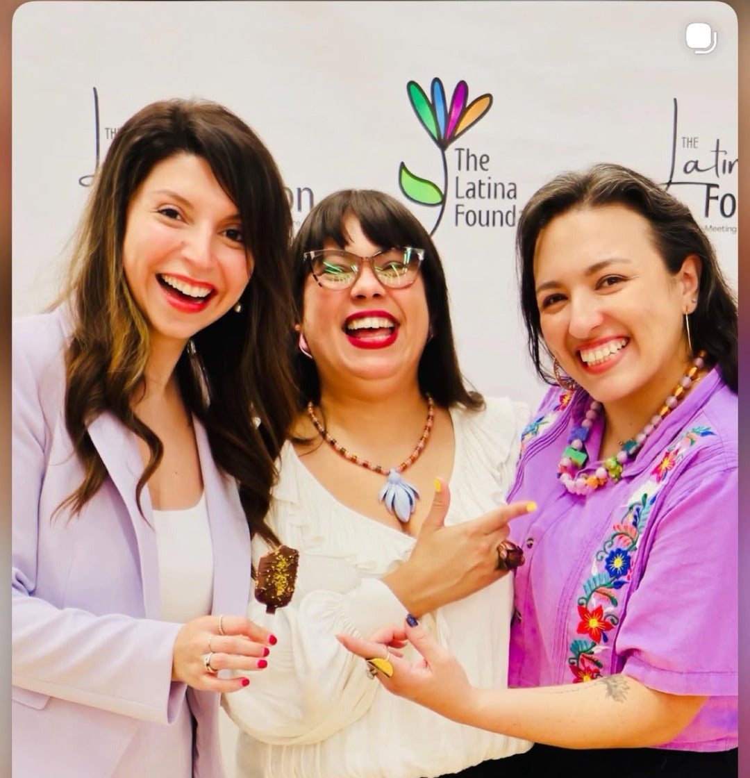 Tres mujeres sonriendo usando joyería CATE en un evento de The Latina Foundation